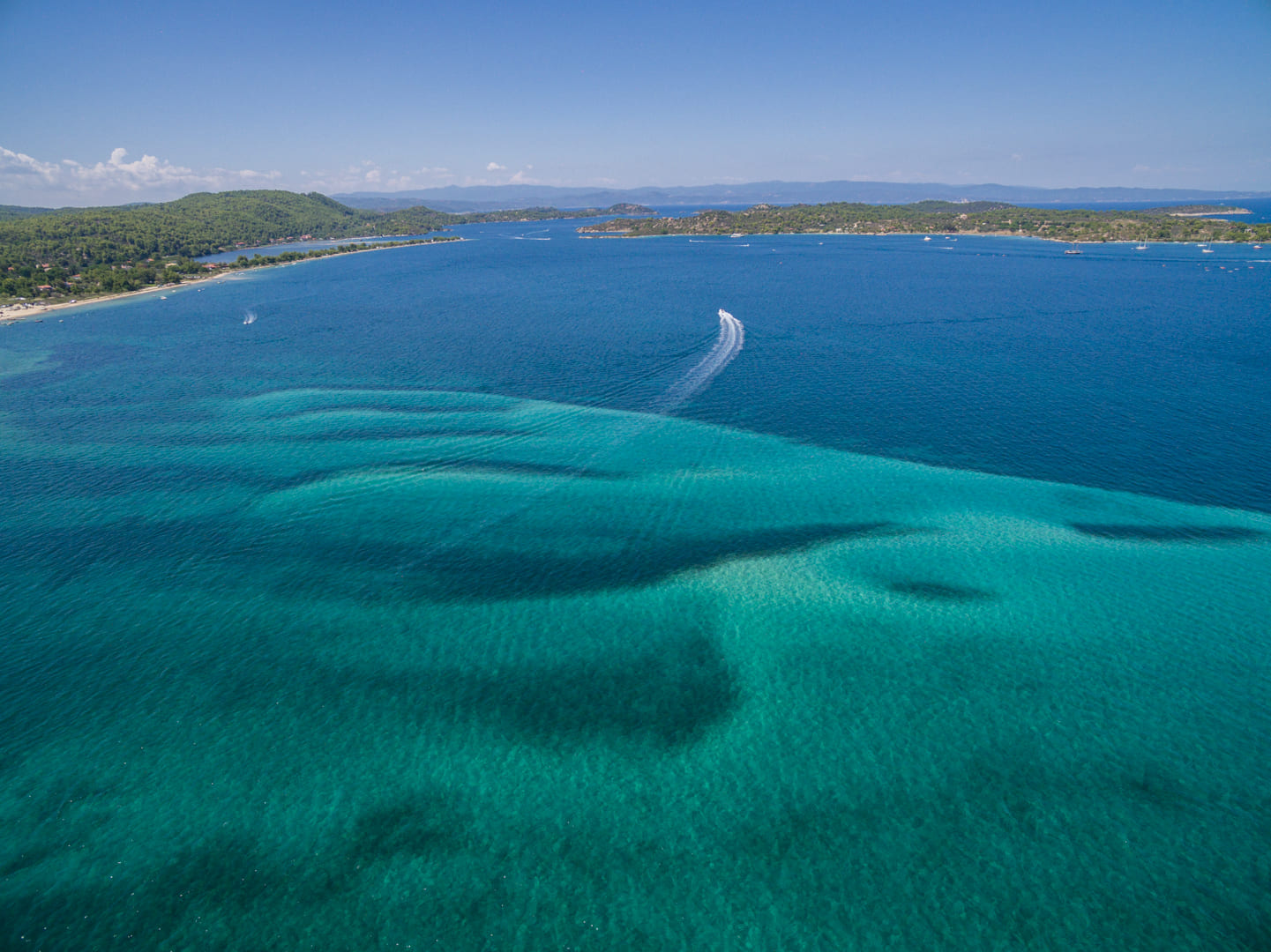 Boat crossing the calm Vourvourou bay, Halkidiki